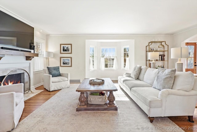 living area with plenty of natural light, a fireplace with flush hearth, arched walkways, and wood finished floors