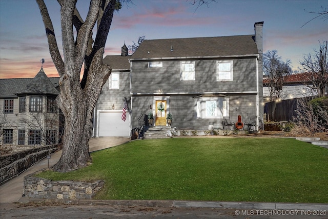 view of front of property featuring a garage, a chimney, fence, and a lawn