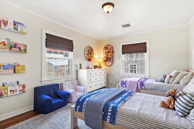 bedroom with baseboards, visible vents, crown molding, and wood finished floors