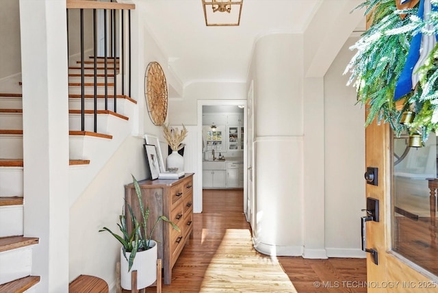 foyer with stairs, light wood finished floors, and crown molding