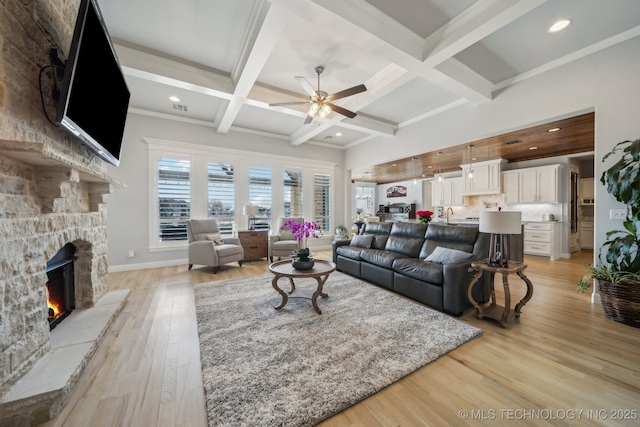 living area featuring light wood-style flooring, a fireplace, coffered ceiling, a ceiling fan, and beam ceiling