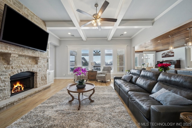 living room featuring baseboards, coffered ceiling, a stone fireplace, light wood-style floors, and beam ceiling