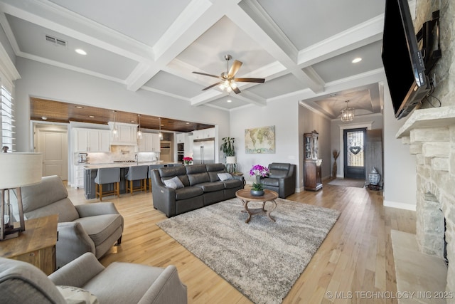 living room with visible vents, coffered ceiling, beam ceiling, and a stone fireplace