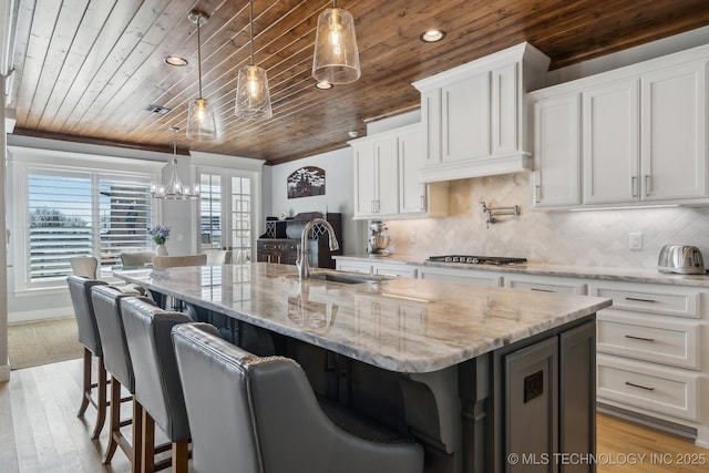 kitchen with pendant lighting, white cabinets, and a kitchen island with sink