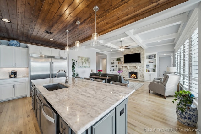 kitchen with a sink, wood ceiling, white cabinets, hanging light fixtures, and an island with sink