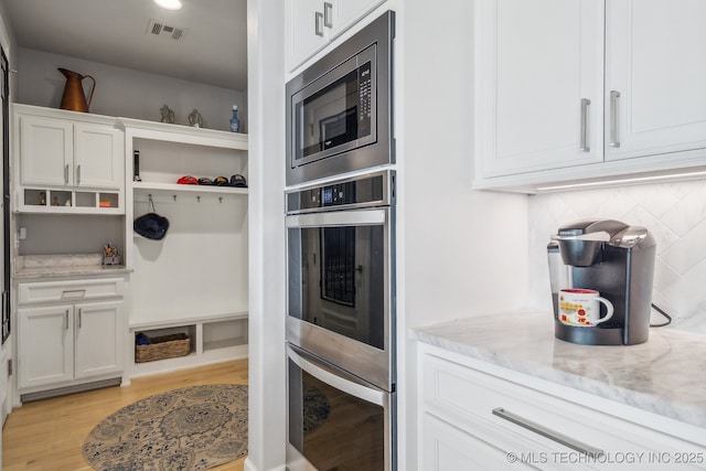 kitchen featuring appliances with stainless steel finishes, light stone counters, white cabinetry, open shelves, and backsplash