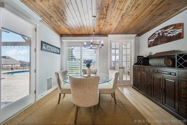 dining space featuring a chandelier, light wood-style flooring, wood ceiling, french doors, and crown molding