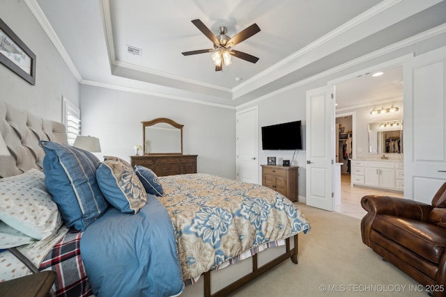 bedroom featuring ceiling fan, light colored carpet, visible vents, a raised ceiling, and ensuite bath