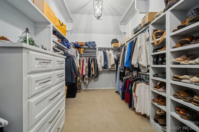 spacious closet with an inviting chandelier and light colored carpet