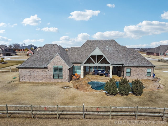 view of front of home with a shingled roof, a fenced backyard, a patio, and brick siding