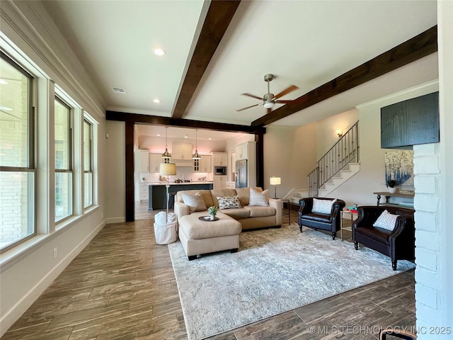 living area featuring beam ceiling, dark wood-type flooring, ceiling fan, baseboards, and stairs