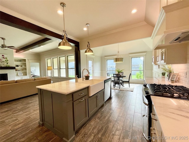 kitchen with decorative light fixtures, a center island with sink, stainless steel appliances, light countertops, and open floor plan