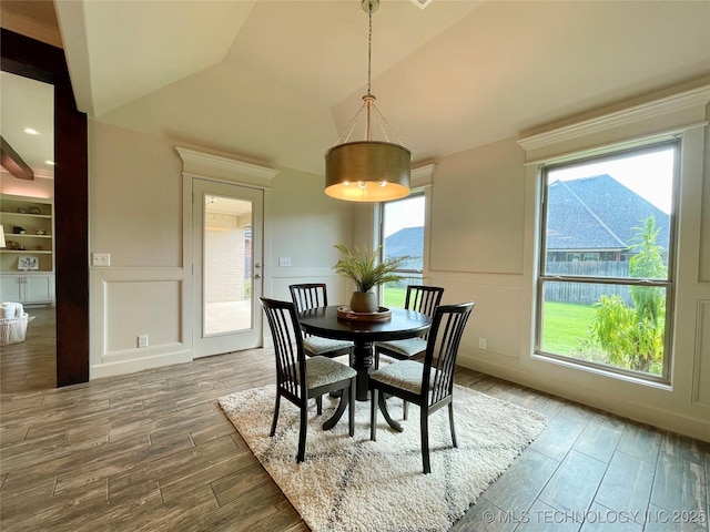 dining room with lofted ceiling, a mountain view, a decorative wall, and wood finished floors