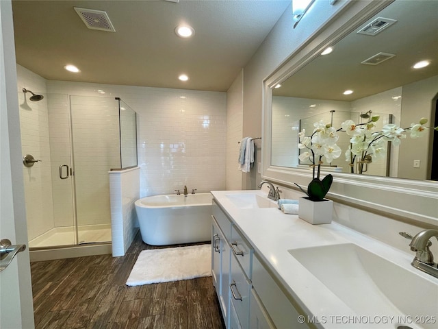 bathroom with a soaking tub, visible vents, a sink, and wood finished floors