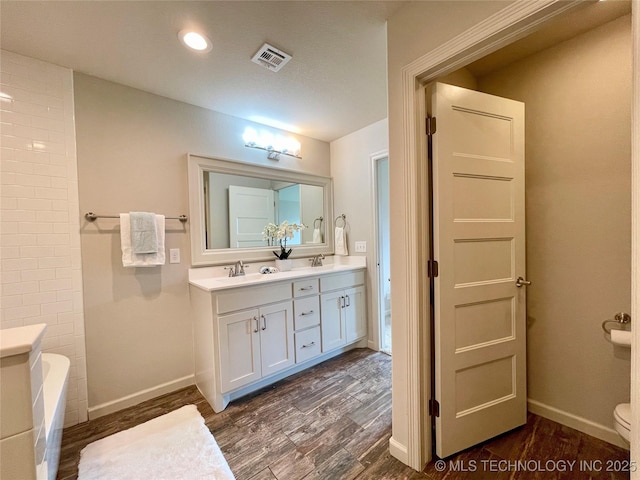 bathroom featuring a tub, visible vents, a sink, and wood finished floors