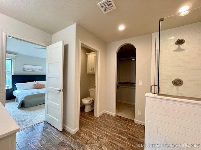 bathroom with visible vents, toilet, a stall shower, ensuite bath, and wood finished floors