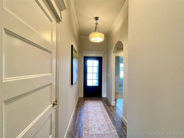 doorway to outside with arched walkways, dark wood-type flooring, baseboards, and crown molding