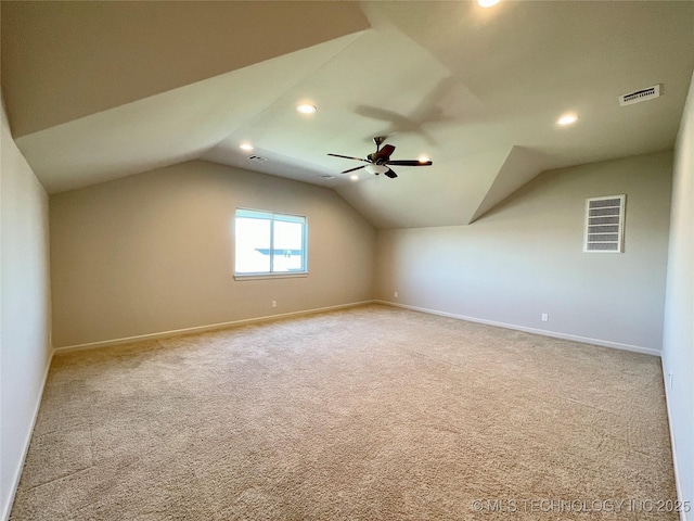 additional living space with light carpet, baseboards, visible vents, a ceiling fan, and vaulted ceiling