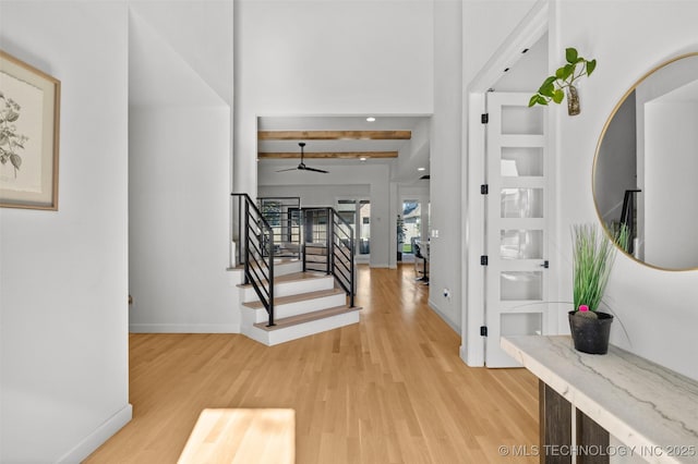 entrance foyer featuring light wood-type flooring, baseboards, stairway, and ceiling fan