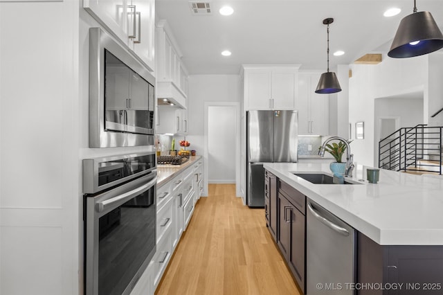 kitchen featuring appliances with stainless steel finishes, white cabinetry, visible vents, and pendant lighting