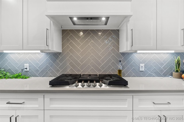 kitchen featuring light countertops, stainless steel gas stovetop, decorative backsplash, and white cabinets