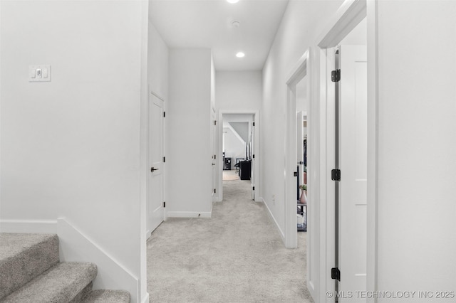 corridor featuring stairs, recessed lighting, baseboards, and light colored carpet