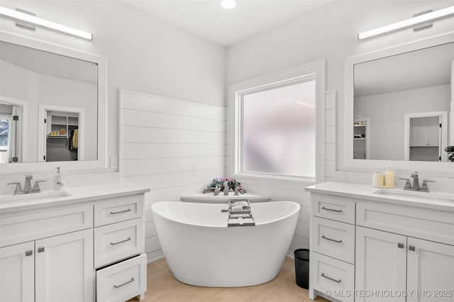 bathroom with a freestanding tub, two vanities, and a sink