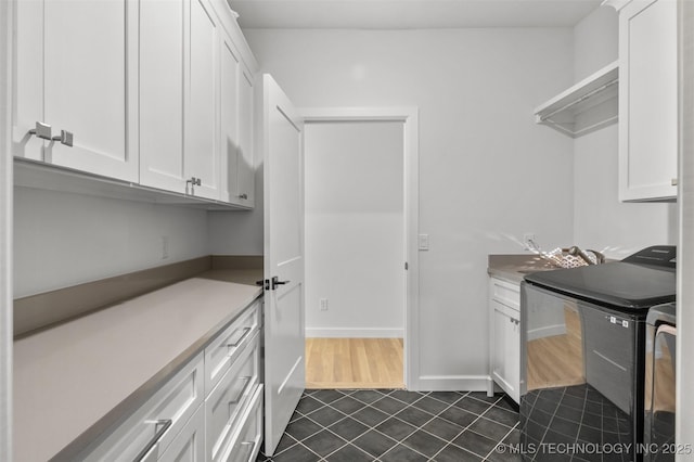 kitchen with dark tile patterned flooring, light countertops, white cabinetry, a sink, and washer and dryer