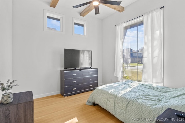 bedroom featuring a ceiling fan, beam ceiling, baseboards, and wood finished floors