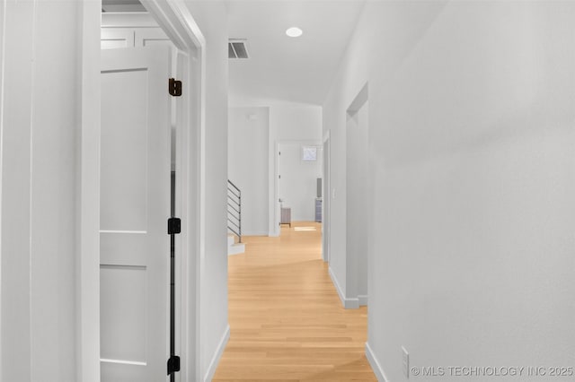 hall featuring light wood finished floors, visible vents, and baseboards