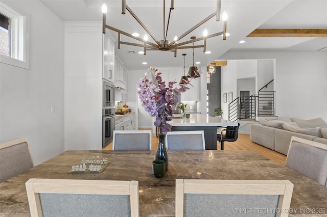 dining space featuring a notable chandelier, stairway, light wood-type flooring, and recessed lighting