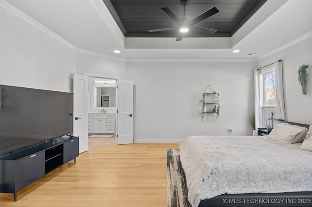 bedroom featuring connected bathroom, a tray ceiling, crown molding, and wood finished floors