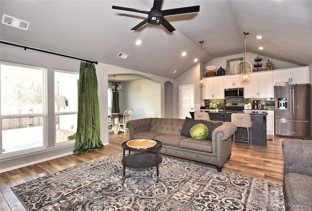 living area with arched walkways, ceiling fan, lofted ceiling, and wood finished floors