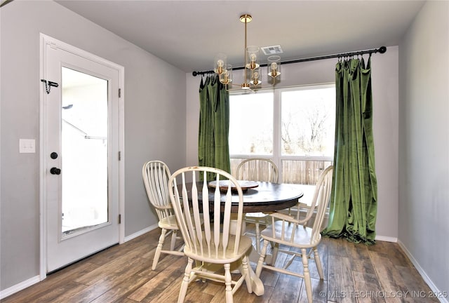 dining space featuring a chandelier, visible vents, baseboards, and wood finished floors