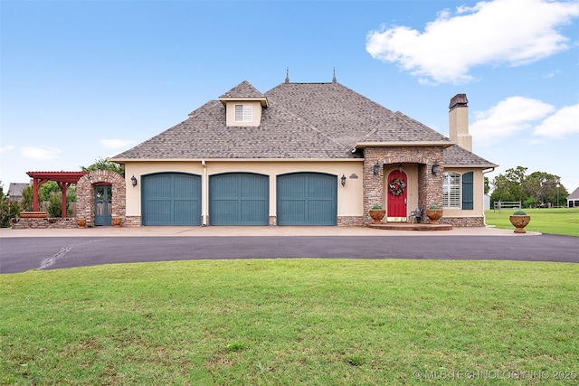 french provincial home with a garage, stone siding, a front lawn, and stucco siding