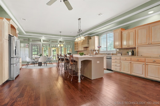 kitchen with an island with sink, hanging light fixtures, light countertops, a kitchen bar, and stainless steel refrigerator with ice dispenser