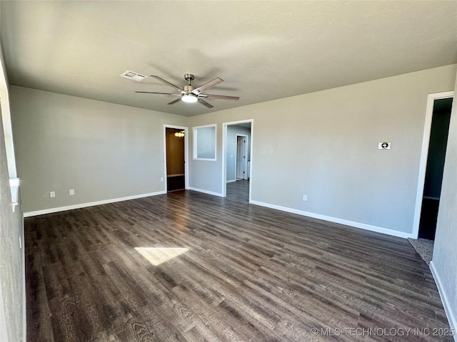 spare room featuring ceiling fan, baseboards, visible vents, and dark wood finished floors