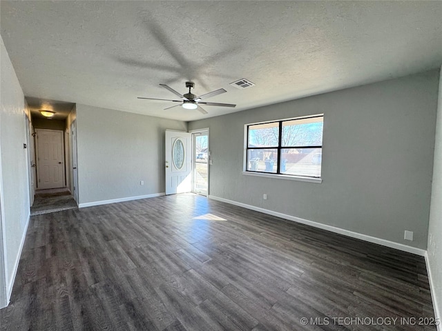 unfurnished room with baseboards, visible vents, a ceiling fan, dark wood-style floors, and a textured ceiling