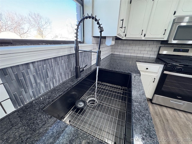 details featuring appliances with stainless steel finishes, white cabinets, and backsplash