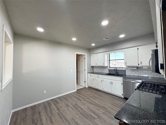 kitchen featuring stainless steel appliances, visible vents, light wood-style floors, white cabinetry, and a sink