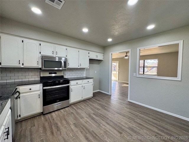 kitchen featuring dark countertops, appliances with stainless steel finishes, white cabinets, and wood finished floors