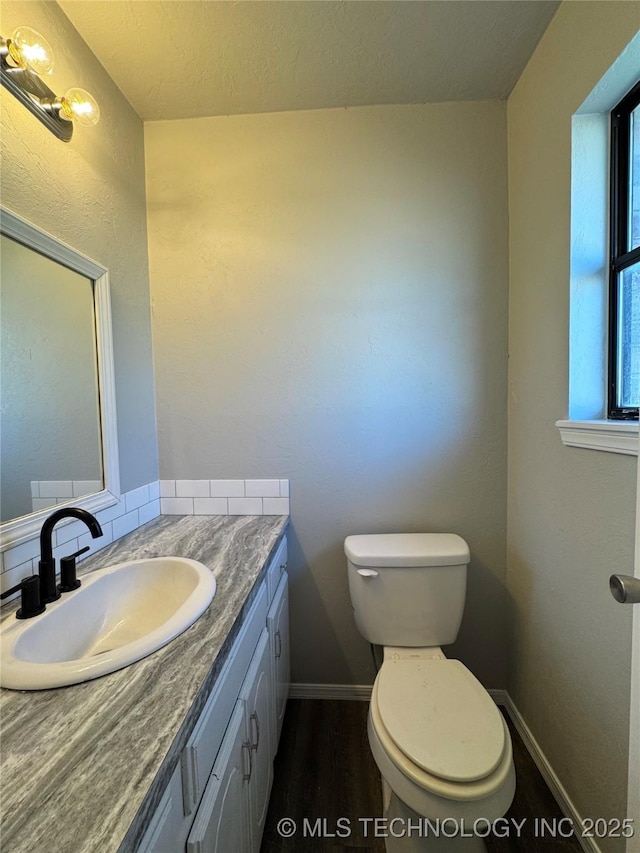 bathroom featuring toilet, wood finished floors, vanity, and baseboards