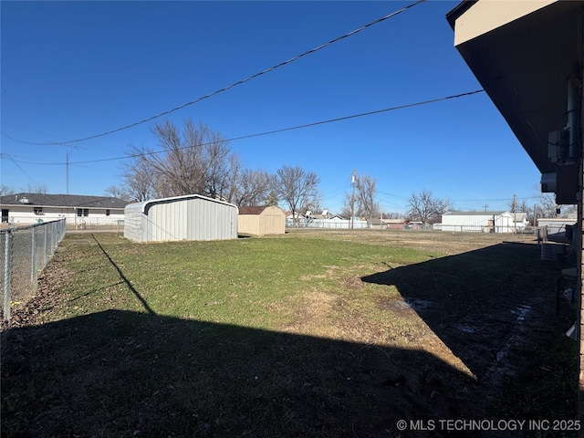 view of yard featuring a storage shed, fence, and an outbuilding