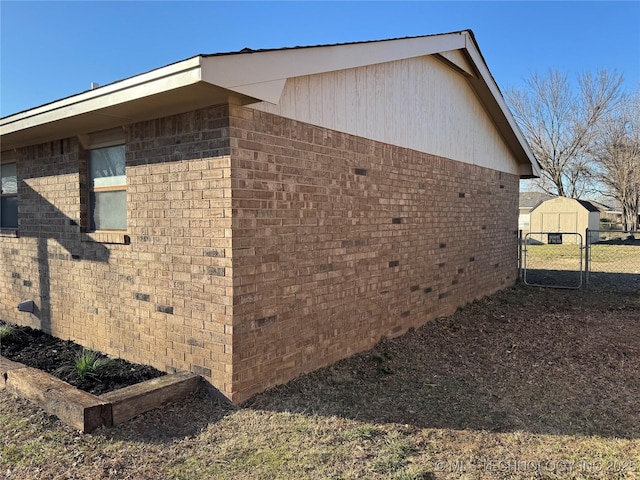 view of property exterior with an outbuilding, a storage shed, brick siding, fence, and crawl space