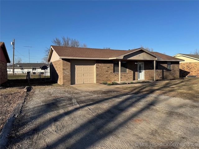 ranch-style home featuring a garage, brick siding, driveway, and fence