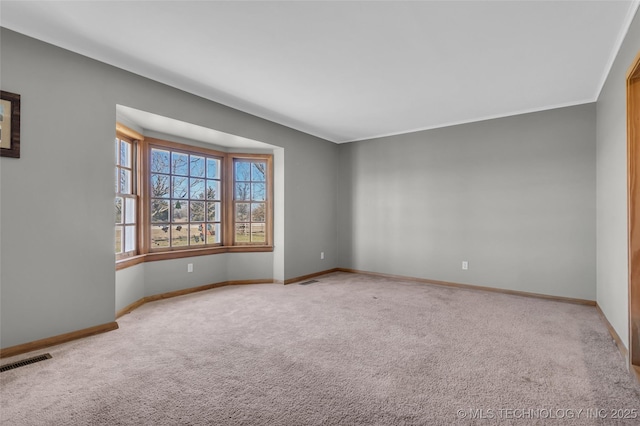 spare room with baseboards, visible vents, and carpet flooring