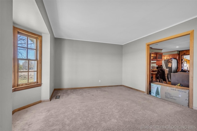 unfurnished room with light carpet, visible vents, baseboards, and ornamental molding