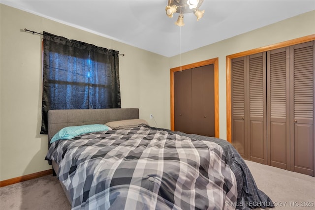 bedroom featuring two closets, a ceiling fan, baseboards, and carpet flooring