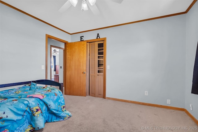 carpeted bedroom with baseboards, ornamental molding, ceiling fan, and a closet