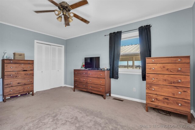 bedroom with baseboards, ornamental molding, a closet, and light colored carpet